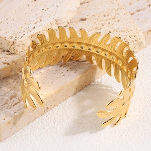 Detailed close-up of golden leaf-shaped open cuff with intricate vein texture and relief