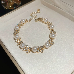 Dettaglio di un bracciale dorato con perle e cristalli a fiori in un portagioie