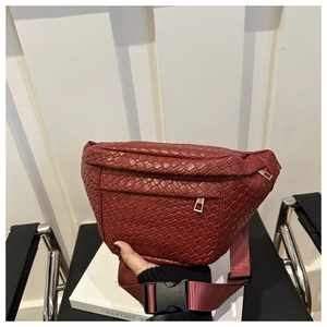 Detailed view of burgundy woven belt bag featuring gold zippers and robust plastic buckle