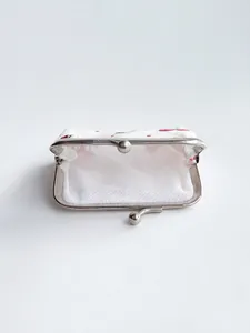 White fabric kiss-lock coin purse with red cherry pattern and vintage metal frame closure