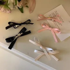 Close-up of sweet bow hair clips in black, pink, and white with metal duckbill clips