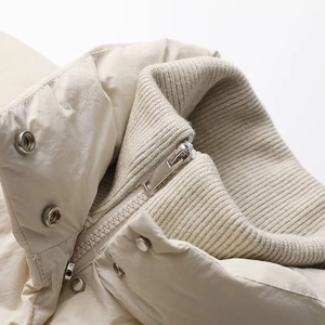 Detailed close-up of ribbed knit collar and silver metal zipper on beige winter coat