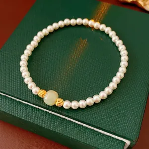Elegant pearl bracelet with a green jade bead and golden spacers on a jewelry box
