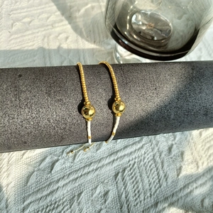 Adjustable geometric gold beads and freshwater pearl bracelet on a display stand