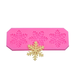 Macro detail of pink snowflake silicone mold with three cavities and white fondant result