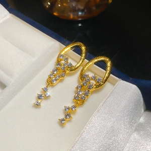 Close-up of gold dangle earrings with sparkling rhinestones on a premium velvet box