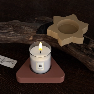 Macro shot of geometric resin candle holders with a lit candle on dark wood background