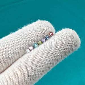 Close-up of curved eyebrow rings with colorful zircon stones on a gloved finger