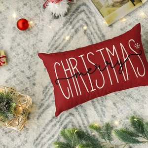 Close-up of red lumbar pillow with Merry Christmas print and festive holiday decorations