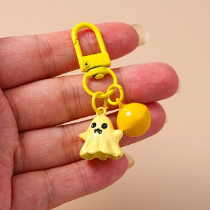 Close-up of yellow cartoon ghost keychain with small bell and D-clasp held by hand