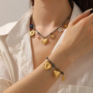 Detail of gold plated heart and star charms on blue braided cord necklace and bracelet
