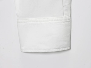 Dettaglio della manica in camicia di cotone bianco con elegante bottone gioiello