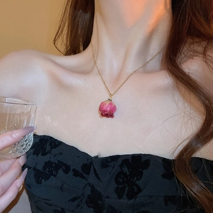 Detail of elegant gold chain necklace featuring a delicate real pink dried rose pendant