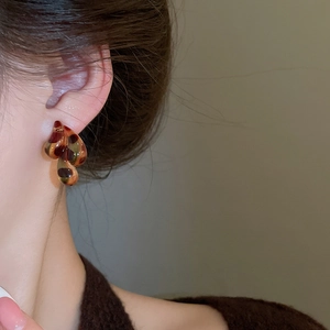 Macro detail of leopard print resin earrings with irregular drop shape on model