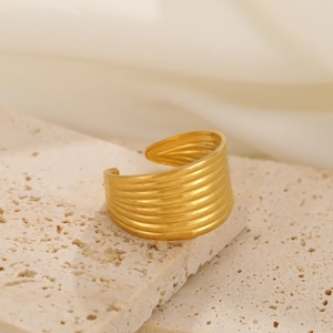 Close-up of golden wide-band corrugated ring featuring a textured water ripple design