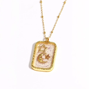 Macro shot of gold sun moon pendant with sparkling resin inlay and bead chain link