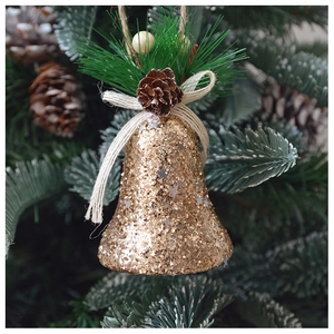 Détail d'une cloche de Noël dorée scintillante avec pommes de pin sur un sapin vert