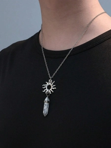 Detail view of a hexagonal white turquoise stone pendant with silver sun charm on a chain