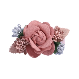 Close-up of pink fabric roses with silver berry accents and green leaves for hair accessories