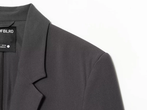 Detail shot of a dark grey blazer collar and shoulder with a textured fabric finish