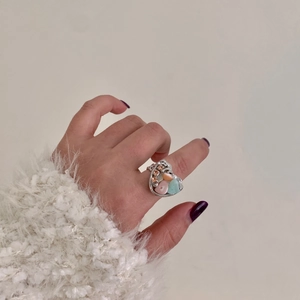 Detail shot of a handmade silver ring featuring colorful pastel stones and crystal accents
