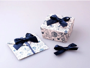 Detailed overhead view of cream gift box and envelope with blue floral patterns and ribbon