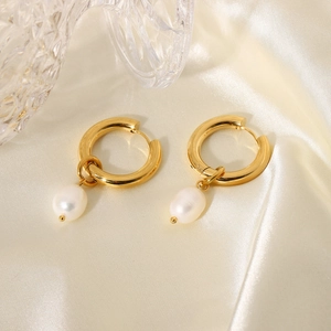 Detail of 18k gold plated hoop earrings with white pearl pendants on champagne silk fabric