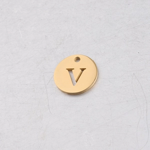 Gros plan d'un pendentif rond de 12 mm en acier inoxydable doré avec lettre V évidée