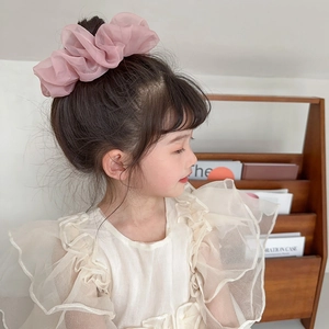 Pink chiffon scrunchie shown on a girl's high bun hairstyle with sweet floral design