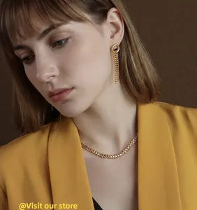 Detail view of 18k gold leaf necklace and circular tassel earrings on model