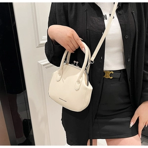 Modern cream white shell handbag with silver metal clasp worn by a fashion model