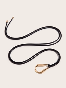 Detail of minimalist black leather knot belt featuring a gold irregular metal buckle