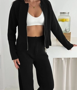 Detail of black knit two-piece set featuring a zipper cardigan and high waist straight pants
