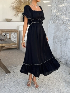 Detail of bohemian black dress with tiered ruffle skirt and white contrast trim accents