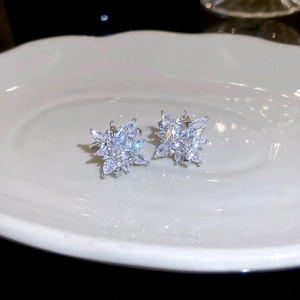 Detailed close-up of sparkling zircon star-shaped ear cuffs on a ceramic tray