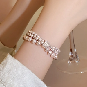 Detail of a three-layer light pink pearl bracelet with a sparkling zircon clasp