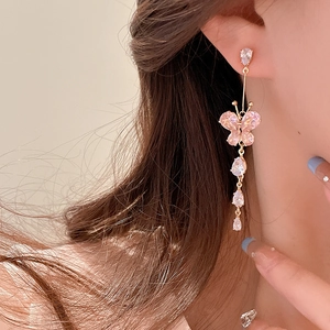 Close-up of elegant gold butterfly tassel earrings with pink zircons on a model