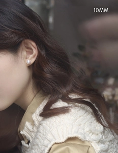 Close-up of 10mm white pearl stud earrings showing elegant mirror luster on a model