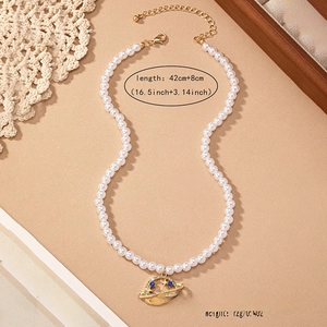 Detail of pearl necklace with golden Saturn pendant featuring blue gems and 42cm length mark