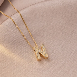 Macro shot of gold plated necklace with letter N pendant pavé set with white zircons