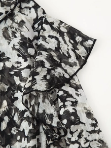 Detaillierte Makroansicht von schwarz-weißem Abstrakt-Print auf leichtem Chiffon mit Rüschen