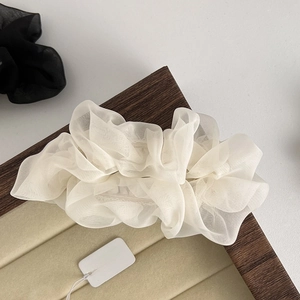 Detailed view of elegant white pleated tulle hair accessory on a wooden display tray