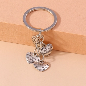 Silver vintage heart keychain with Love You engraved pendants on a peach-colored block