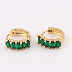Detailed shot of golden hoop earrings featuring inlaid emerald green rectangular crystals