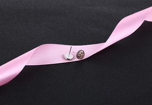 Close-up of S925 silver stud earrings with pink crystal clusters on soft pink silk ribbon