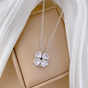 Close-up of a versatile heart-shaped clover necklace with sparkling crystals on silk fabric