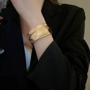 Close-up of golden chunky cuff bracelet with irregular hammered texture on model