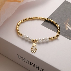 Detailed close-up of beaded bracelet with white pearls and gold girl pendant
