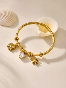 Detailed view of a gold bangle with bear, heart crystal, and elephant charms