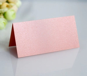 Detail of pink glitter table card with laser-cut butterfly on a reflective surface